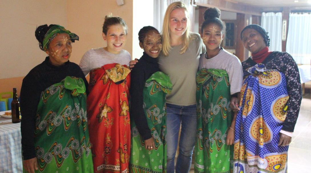 Projects Abroad volunteers with their host family, who helped the volunteers practice their French Projects Abroad volunteers posing with a family in Madagascar wearing traditional Malagasy clothing